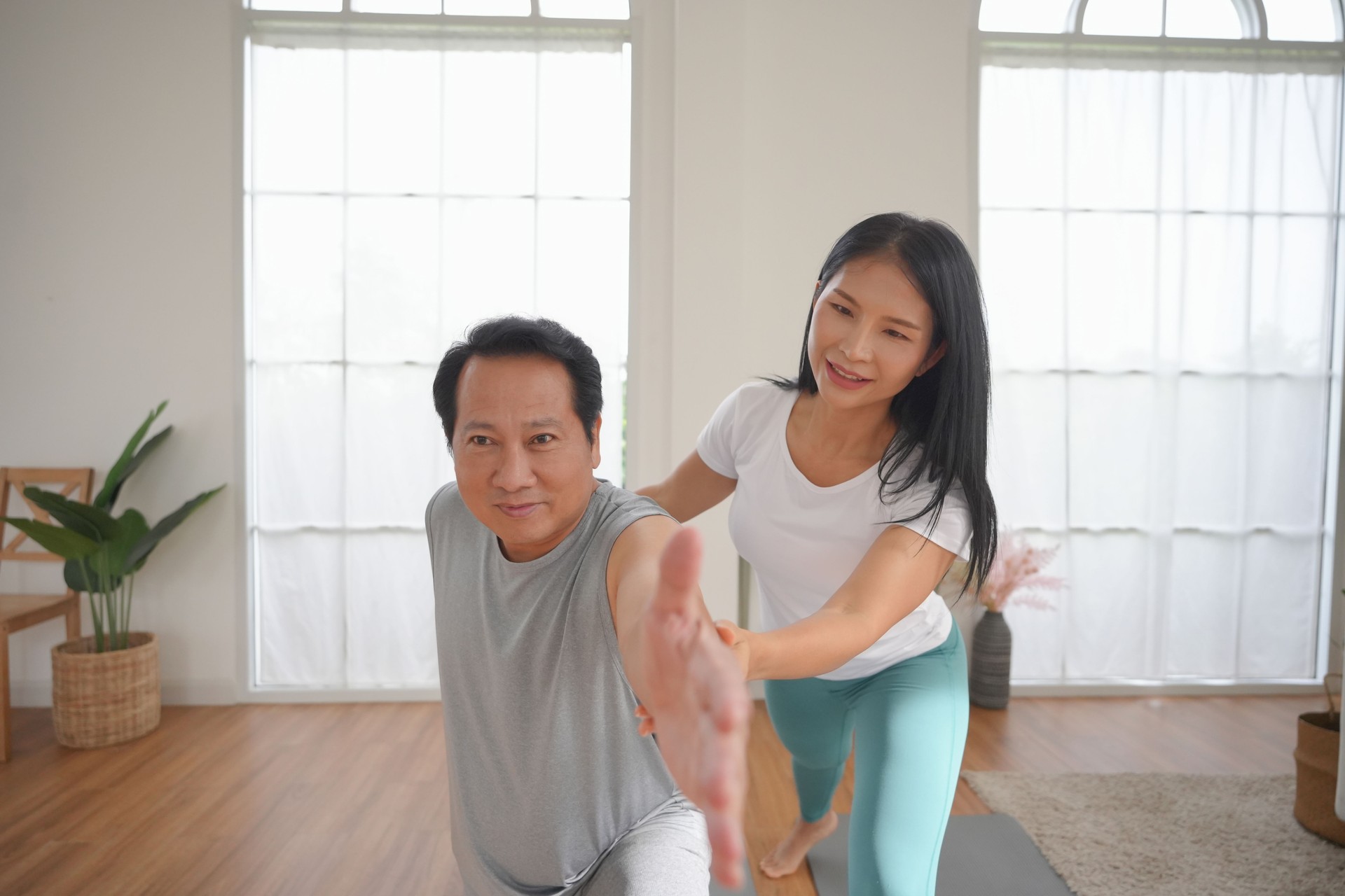 Asian Male and female pair engage in calm yoga session together